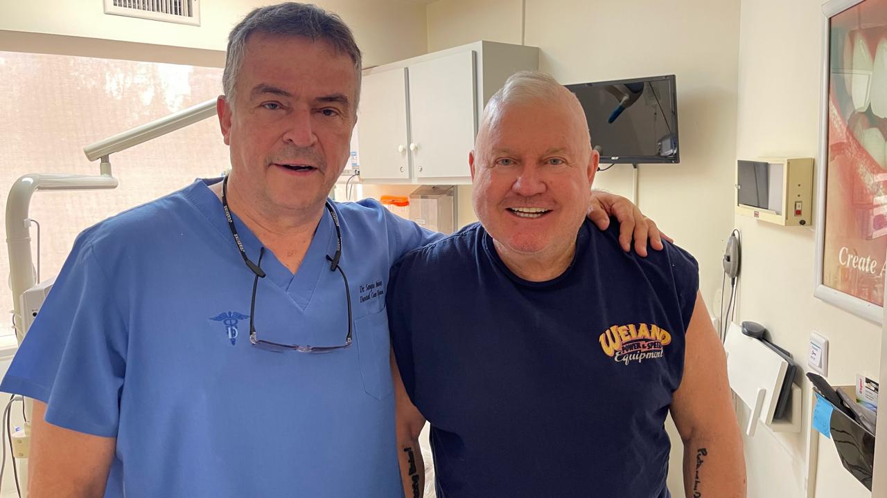 Dentist consulting with a smiling patient in the treatment area